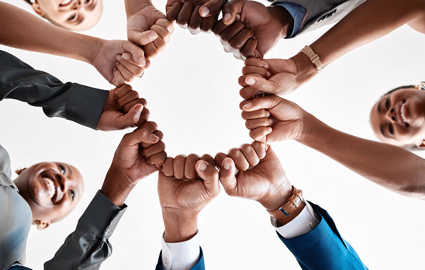 Many people creating a circle with their fists in the center